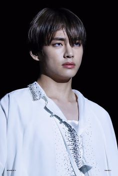 a young man wearing a white shirt and tie with his eyes wide open, standing in front of a black background