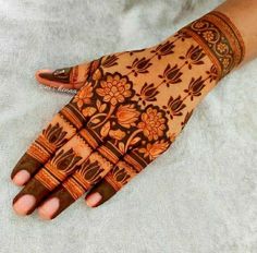 a woman's hand with henna on it and flowers painted on the palm