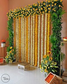 an arrangement of yellow flowers and greenery on the side of a wall in a room