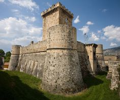 an old castle like structure on the side of a hill with grass in front of it