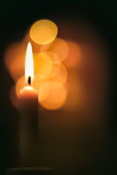 a lit candle with blurry lights in the background