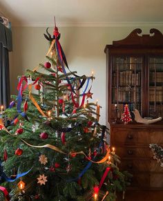 a decorated christmas tree with red, white and blue ribbons on it in a living room