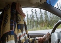 a person sitting in the passenger seat of a car with a blanket over their head