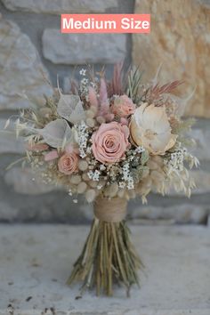 a bouquet of flowers sitting on top of a wooden table next to a stone wall