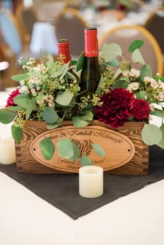 a wooden box with flowers and wine bottles in it sitting on top of a table