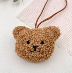 a brown teddy bear keychain hanging on a white towel