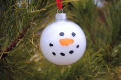 a snowman ornament hanging from a christmas tree in the shape of a ball