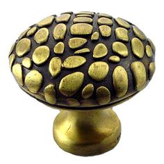 an antique brass knob with black and gold dots on the top, against a white background