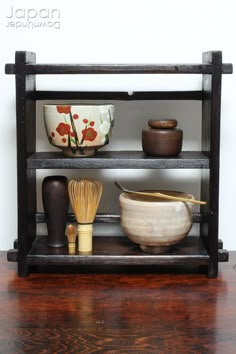 a shelf with bowls, whisk and other kitchen items on top of it