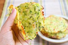 a person holding up a piece of broccoli frittata in front of a plate