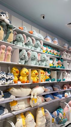 many stuffed animals are on shelves in a store