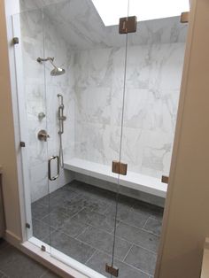 a walk in shower sitting next to a white bath tub under a skylight on top of a tiled floor