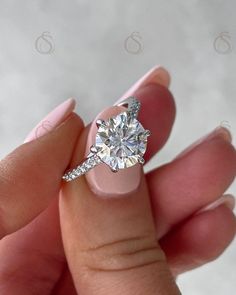 a woman's hand holding an engagement ring with a diamond on the top and side