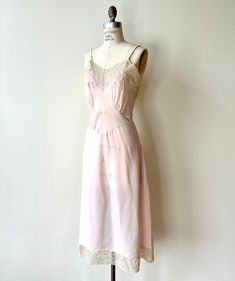 Beautiful 1940s Deadstock slip in light pink rayon with flower embroidered neckline and lace detailing. Beautiful ppeaked empire waist for a perfect slimming effect and bias cut for a slinky fit.  Best fits a small with adjustable straps and bias cut for an easy fit. In excellent, never worn condition with original tags. Bust: Up to 35" Waist: Up to 29.5" Length: 47" (from base of neck to hem) Feminine Fitted Slip Dress With Delicate Lace, Vintage Satin Slip Dress For Spring, Vintage Slip Dress For Wedding, Pink Fitted Slip Dress For Daywear, Vintage Lace Slip Dress For Evening, Fitted Vintage Silk Slip Dress, Vintage Lace Trim Slip Dress For Wedding, Vintage Lace Evening Slip Dress, Vintage Spring Wedding Slip Dress