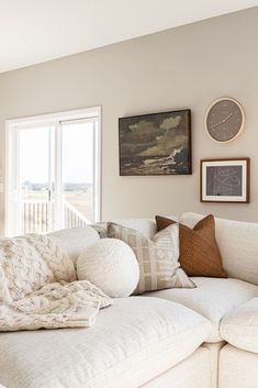 a living room filled with white furniture and lots of pillows on top of the couch