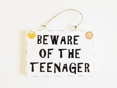 a sign that says beware of the teenager with emoticions on it hanging from a string