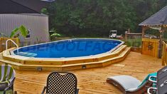 an above ground pool surrounded by wooden decking and patio furniture with chairs around it