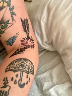 a person laying in bed with tattoos on their legs and arm, holding an umbrella