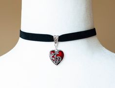 This choker is made from black velvet ribbon and a red, heart shaped pendant embellished with antique silver filigree. - The choker measures 12 inches/30.5cm in length and 0.4 inches/10mm wide - The pendant is approximately 1 inch long and 0.75 inch wide - The choker closes with a lobster claw clasp at the back - One size fits most (for a neck of about 12.5 inches). there is a 2 inch extension chain at the back to accommodate larger neck sizes SHIPPING: Default shipping is by regular mail, which Gothic Heart-shaped Wedding Jewelry, Gothic Heart Pendant Necklace, Gothic Heart Charm Choker Jewelry, Victorian Heart Pendant Jewelry For Valentine's Day, Ornate Pendant Jewelry For Valentine's Day, Red Heart-shaped Engraved Jewelry, Red Engraved Heart-shaped Jewelry, Victorian Heart Pendant Necklaces For Valentine's Day, Gothic Jewelry For Valentine's Day Formal