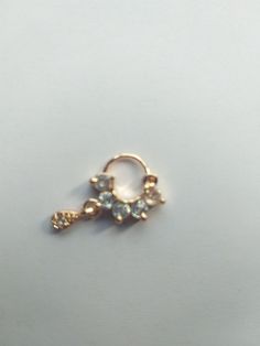 an image of a gold nose ring with flowers on the front and back side, sitting on a white surface