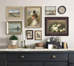 a black dresser with pictures on the wall above it and a clock mounted to the wall