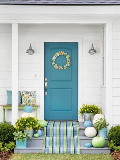 a blue front door with flowers and potted plants