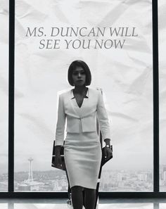 a woman walking down a runway in front of a large poster with the words ms duncan will see you now