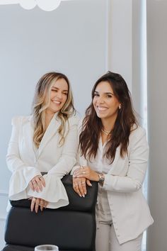 two women sitting next to each other in front of a table with drinks on it