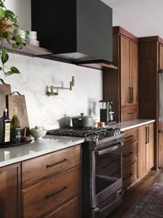 a kitchen with marble counter tops and wooden cabinets, along with an oven hood over the range