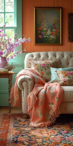 a white couch sitting in front of a window next to a vase filled with flowers