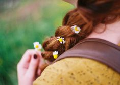 a woman with red hair and flowers in her hair is looking down at the ground