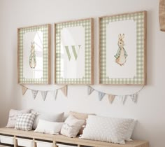 three framed pictures hang on the wall above a bench with pillows and baskets underneath it