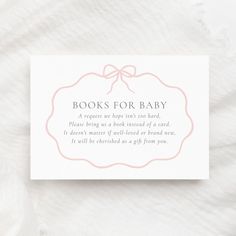 a book for baby card sitting on top of a white sheet with a pink bow