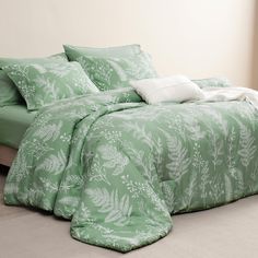 a bed with green comforter and pillows on it