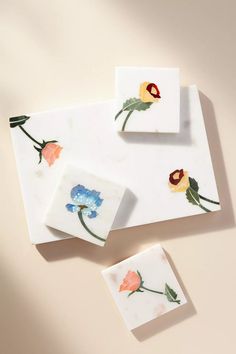 three coasters with flowers painted on them