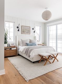 a bedroom with white walls and wood flooring has a large bed in the center