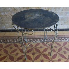 an old metal table sitting on top of a tiled floor