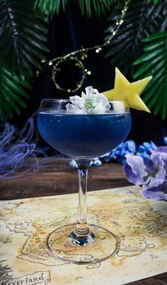 a blue cocktail in a wine glass with a star decoration on the rim and garnish