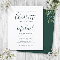 the green and white wedding stationery is displayed on a wooden surface with flowers around it