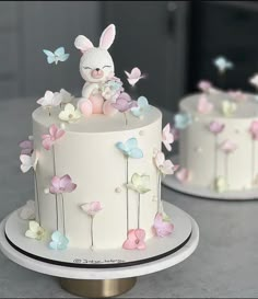 there is a white cake decorated with butterflies and a bunny sitting on top of it