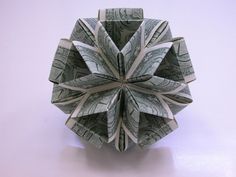 an origami flower made out of one hundred dollar bills on a white surface