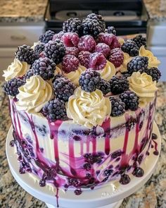 there is a cake with berries and cream on the top, sitting on a counter