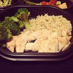 a plastic container filled with rice, broccoli and chicken next to other foods