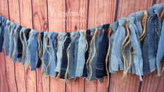 an old pair of jeans hanging from a clothes line on a wooden wall with rope