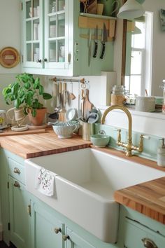 a kitchen filled with lots of green cabinets and wooden counter tops next to a white sink