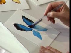 a person is holding a paintbrush and painting butterflies