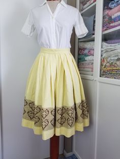 "Sweet little summery skirt! This is made with a buttery yellow textured weave cotton fabric. The skirt is pleated to a flat waistband, and there is a cute border in brown with surface embroidery with hearts. I think it was all hand done! So much time went into this as I believe it to be hand done! This skirt closes in the back with a metal zipper ans a sweet little daisy / flower button! Condition: Very good! One small spot on skirt. On the inside you can see where the brown embroidery thread w Fitted Cotton Pleated Skirt For Daywear, Retro Fitted Cotton Pleated Skirt, Yellow Gathered Cotton Skirt, Cotton Accordion Pleated Skirt, Summer Cotton Skirt With Accordion Pleats, Vintage Cotton Pleated Skirt, Vintage Pleated Cotton Skirt, Vintage Yellow Cotton Skirt, Surface Embroidery