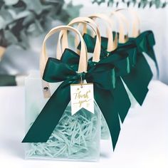 small clear gift bags with green ribbon tied around the top and tags attached to them