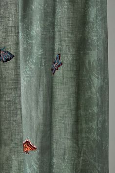 three butterflies are flying in the air on a green curtain with an intricately designed pattern