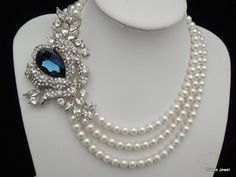 "This glamorous necklace has a dramatic brooch and Swarovski pearls in white. Brooch measures 4 1/4\" by 2 3/4\" at it widest point, and has a huge Swarovski teardrop crystal (30x20mm) in Montana blue placed in the middle surrounded with clear rhinestones. i also had added Swarovski crystal navettes. This multiple strand necklace measures 17 1/2\" long inner strand. Pearls measure 8 mm. Finished off with a silver filigree clasp attached to a lobster claw clasp, enhanced with Swarovski crystals. Blue Pearl Chain Necklaces For Wedding, Blue Pearl Chain Necklace For Wedding, Blue Pearl Chain Jewelry For Wedding, Wedding Necklace Pearl, Bridal Pearl Necklace, Pearl Necklace Wedding, Swarovski Crystal Necklace, Brooch Necklace, Necklace Wedding